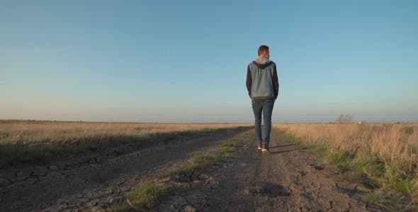 Young Man Walking Away Down a Rural Road